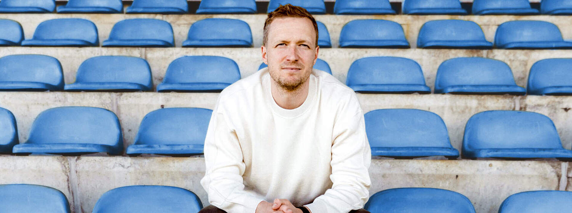 Maximilian Senft sitzt auf der Tribüne eines Stadions.