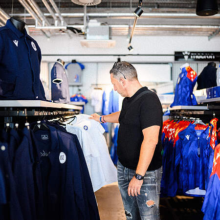 Ein Mann schaut sich in der KSC-FanWelt ein T-Shirt an