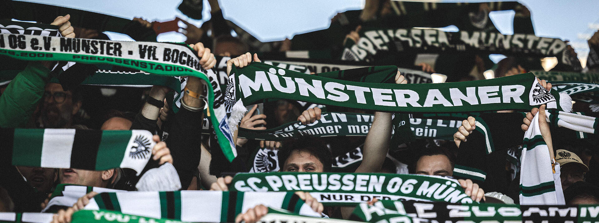Münsteraner Fans halten Schal hoch