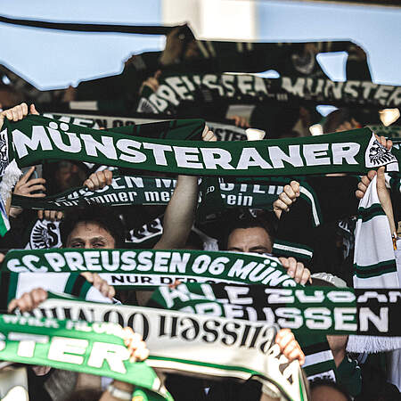 Münsteraner Fans halten Schal hoch