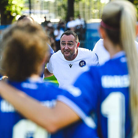 Trainer Christopher Holzer spricht im Teamkreis zu seiner Mannschaft.