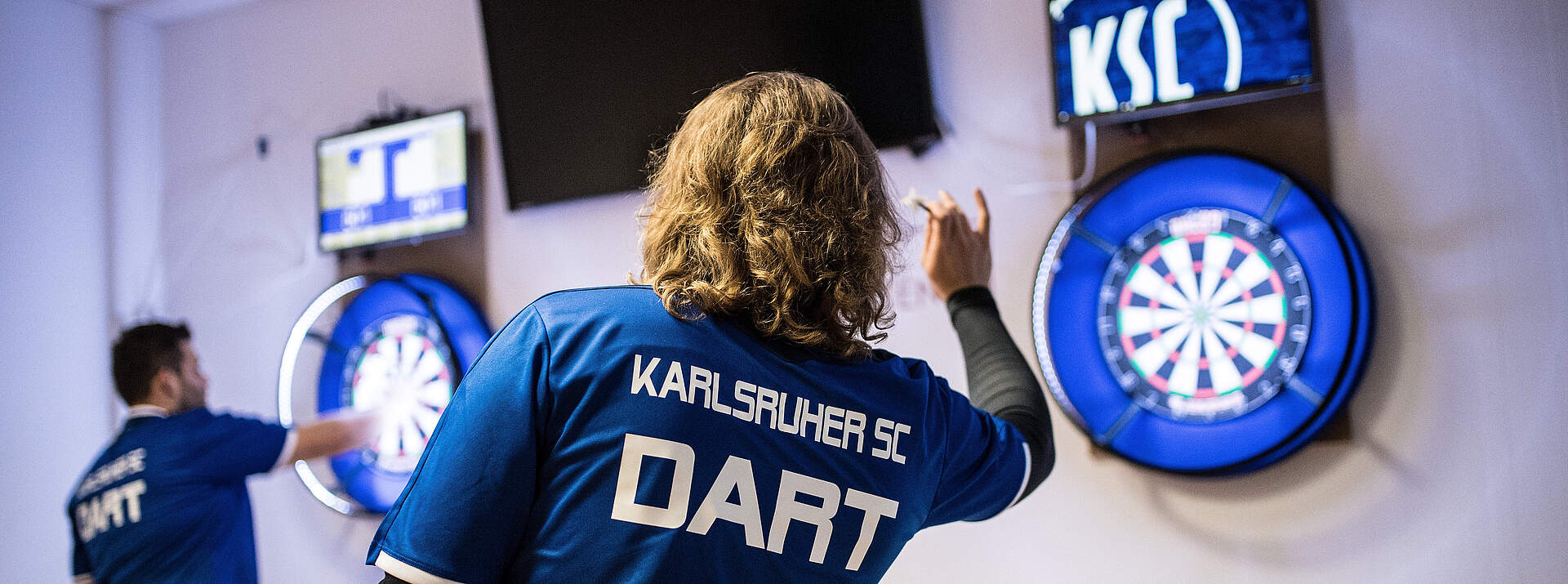 Ein KSC-Spieler wirft einen Dart auf die Scheibe.