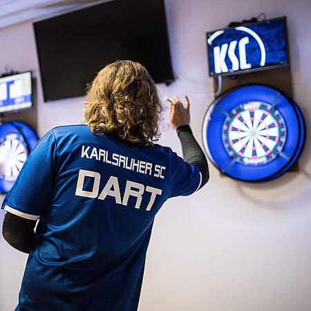 Ein KSC-Spieler wirft einen Dart auf die Scheibe.