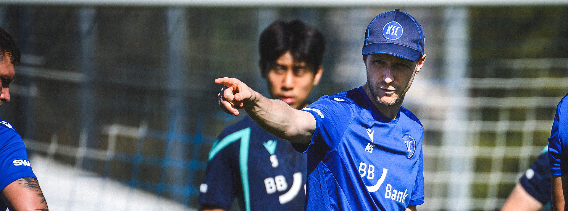 Trainer Max Senft zeigt mit seinem rechten Arm nach vorne.